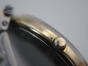 Close-up of the watch case side, showing the crown and a clear "PLAQUE G 10M" engraving indicating 10 micron gold plating.