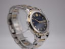 Another angled side view of the watch, emphasising the distinctive gold-tone grooved bezel and the clarity of the blue dial.