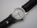 Angled front view of the Michel Herbelin watch, showcasing the white dial, gold bezel, and black leather strap with 'M' logo.