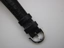 Close-up of the polished stainless steel pin buckle on the black leather strap.