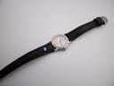 Full length view of the Michel Herbelin watch with its black leather strap laid flat.