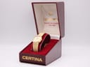 Front view of a gold-plated Certina quartz watch with a champagne dial, presented open in its original red Certina box with gold lettering.
