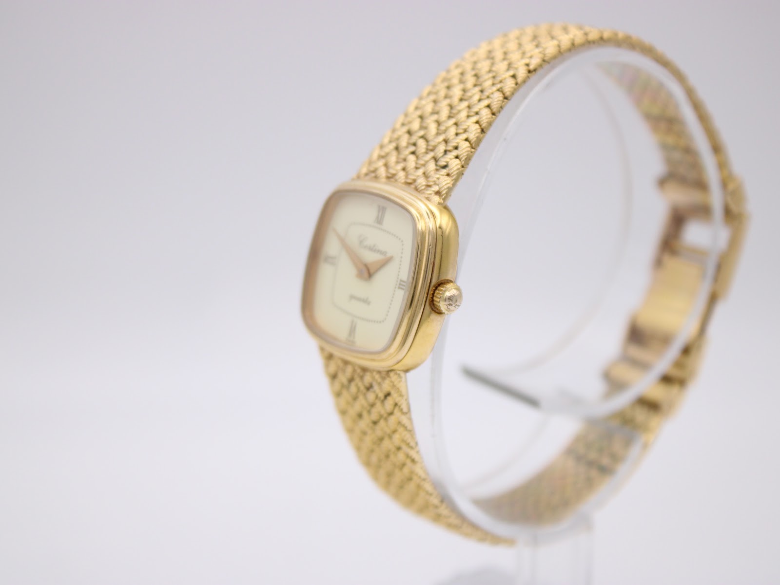 Angled side view of the Certina quartz watch on a display stand, highlighting the side of the gold-plated case and the crown.