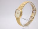 Angled side view of the Certina quartz watch on a display stand, highlighting the side of the gold-plated case and the crown.