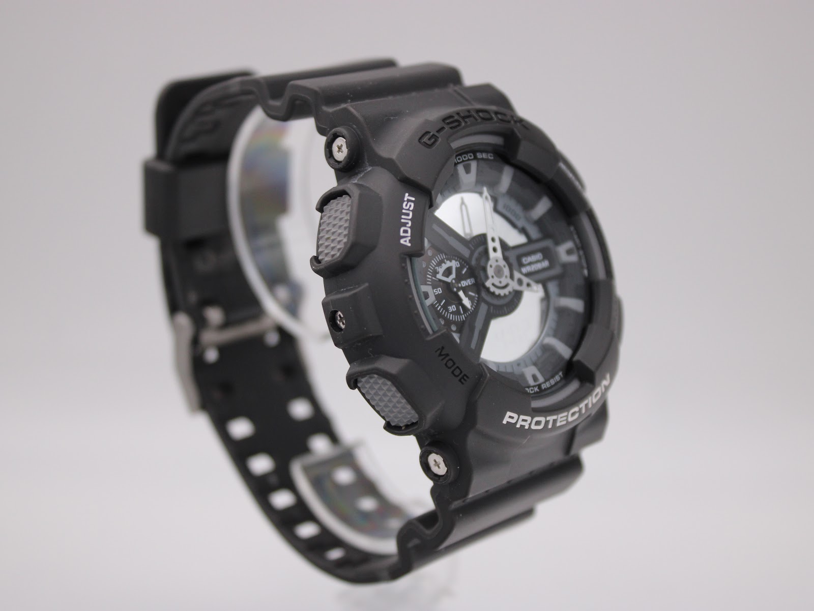 Angled side view of black Casio G-Shock GA-110C watch, highlighting the "ADJUST" and "MODE" buttons.