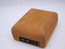 A front-facing view of the closed Maurice Lacroix watch box, made of a textured brown velvet-like material with the brand name on the front.