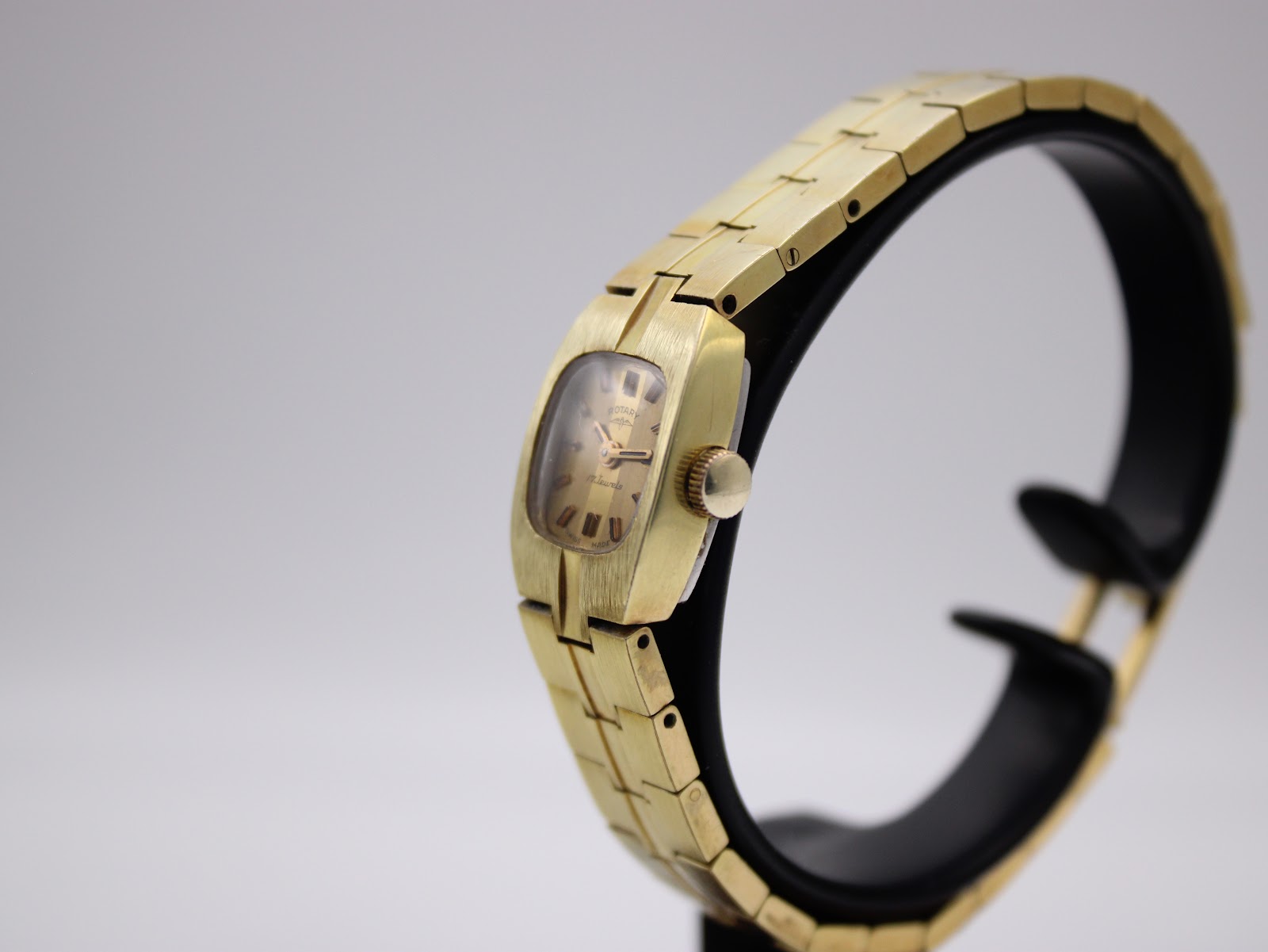 Three-quarter view of the Rotary watch on a display stand, highlighting the brushed gold-plated case and integrated bracelet.