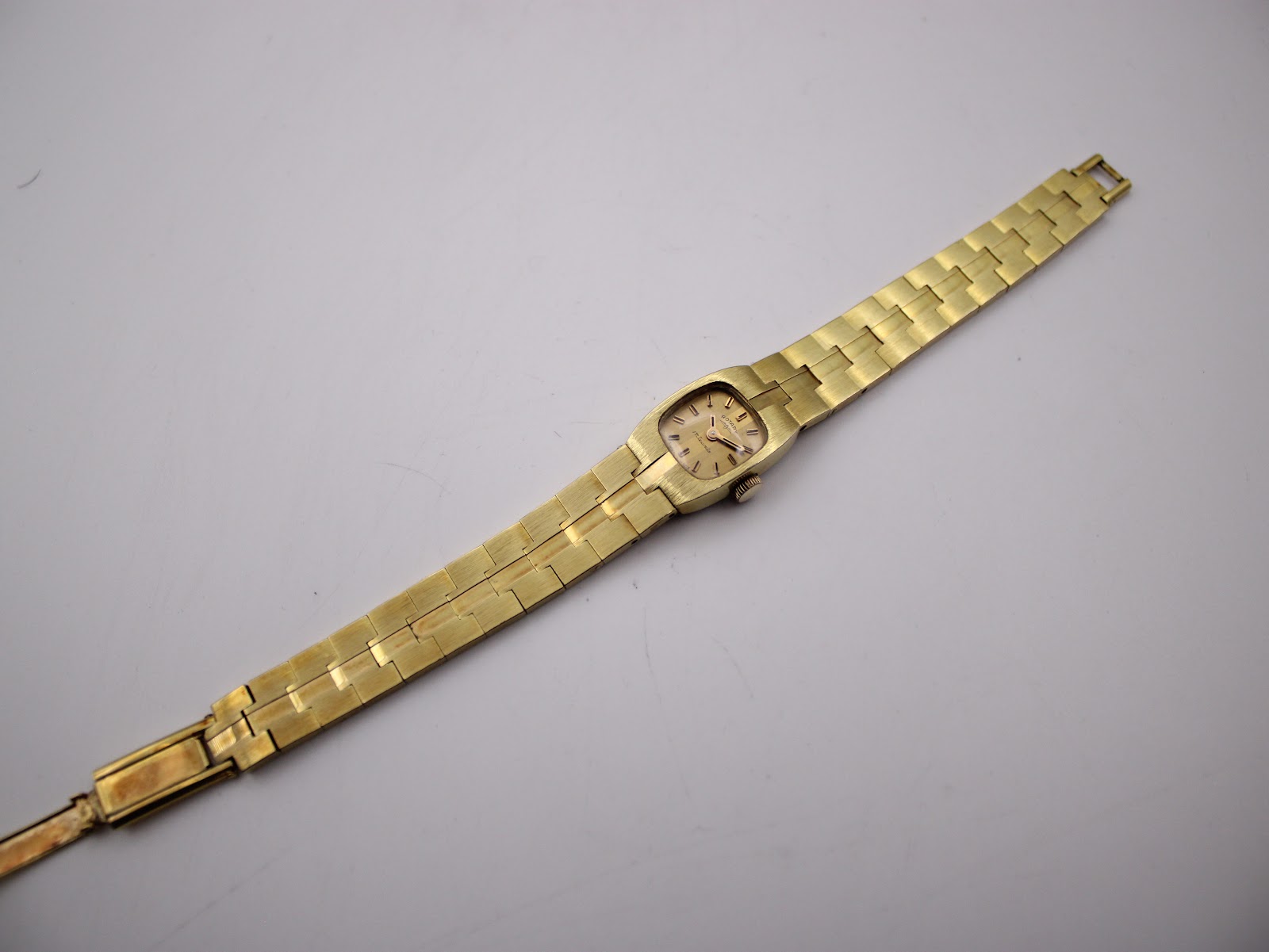 Overhead view of the entire Rotary watch, extended flat, showing the full length of the integrated gold-plated bracelet.
