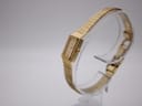 Angled side view of the Rotary watch on a clear stand, highlighting the rectangular case and the mesh bracelet's texture.