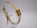 Another angled view of the gold tone Rotary watch, showing the bracelet leading to the clasp and safety chain.