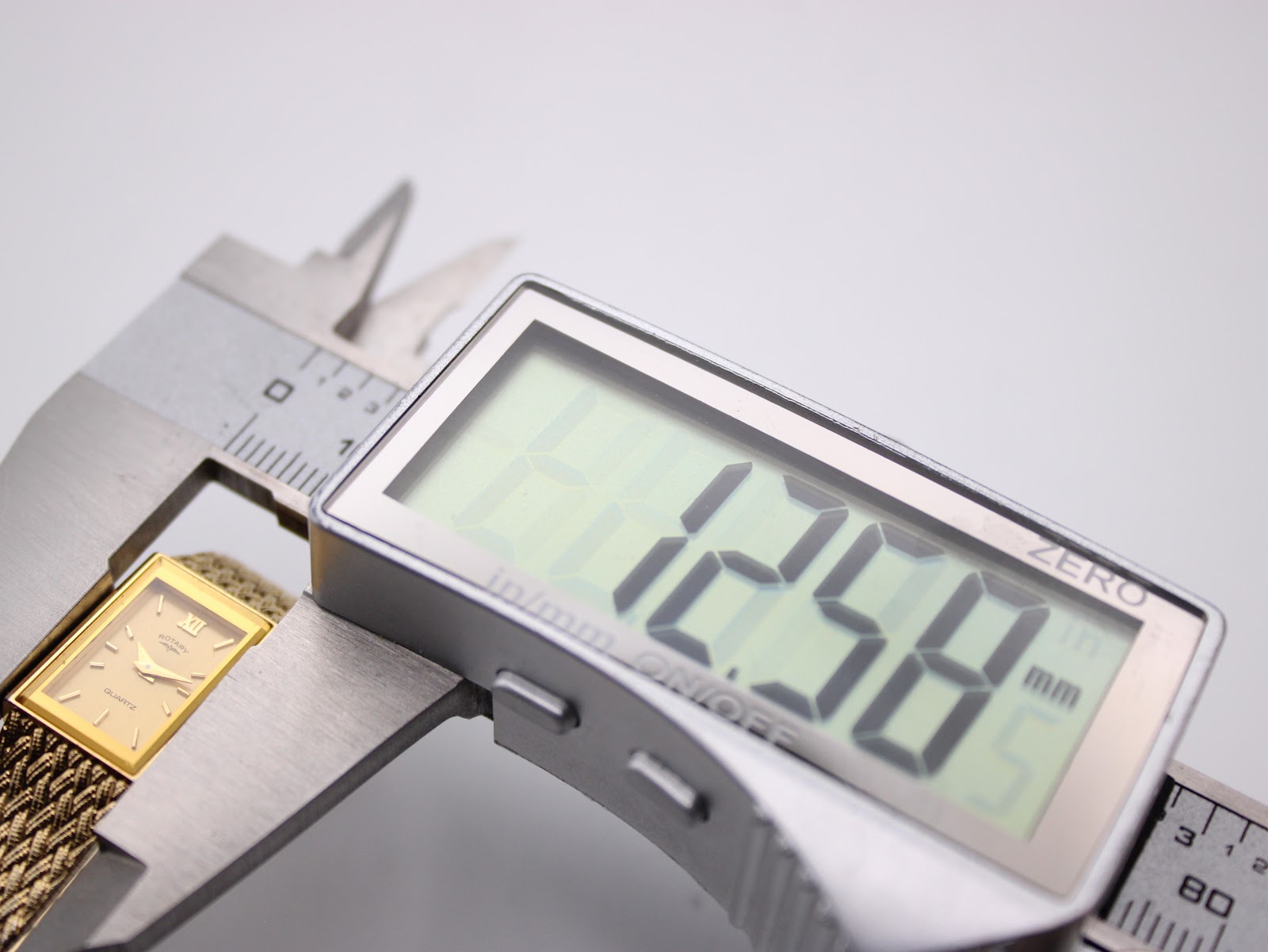 Digital caliper measuring the case width of the Rotary watch, displaying 12.58mm on the screen.