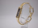 Angled side view of Gucci 1500L watch on a clear display stand, showing the crown and integrated bangle bracelet.