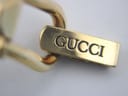 Close-up of the gold tone integrated clasp, clearly showing 'GUCCI' engraved on the surface with some wear.