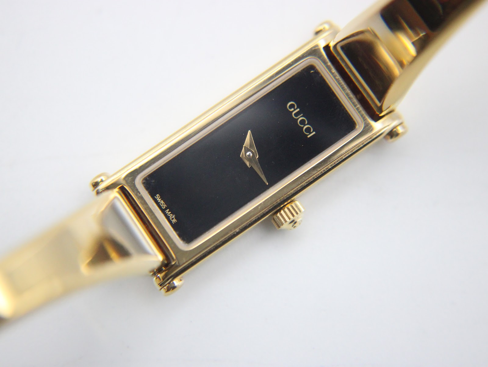 High-angle view of the Gucci 1500L watch dial and integrated bracelet, showing the black minimalist face.
