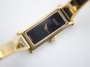 High-angle view of the Gucci 1500L watch dial and integrated bracelet, showing the black minimalist face.