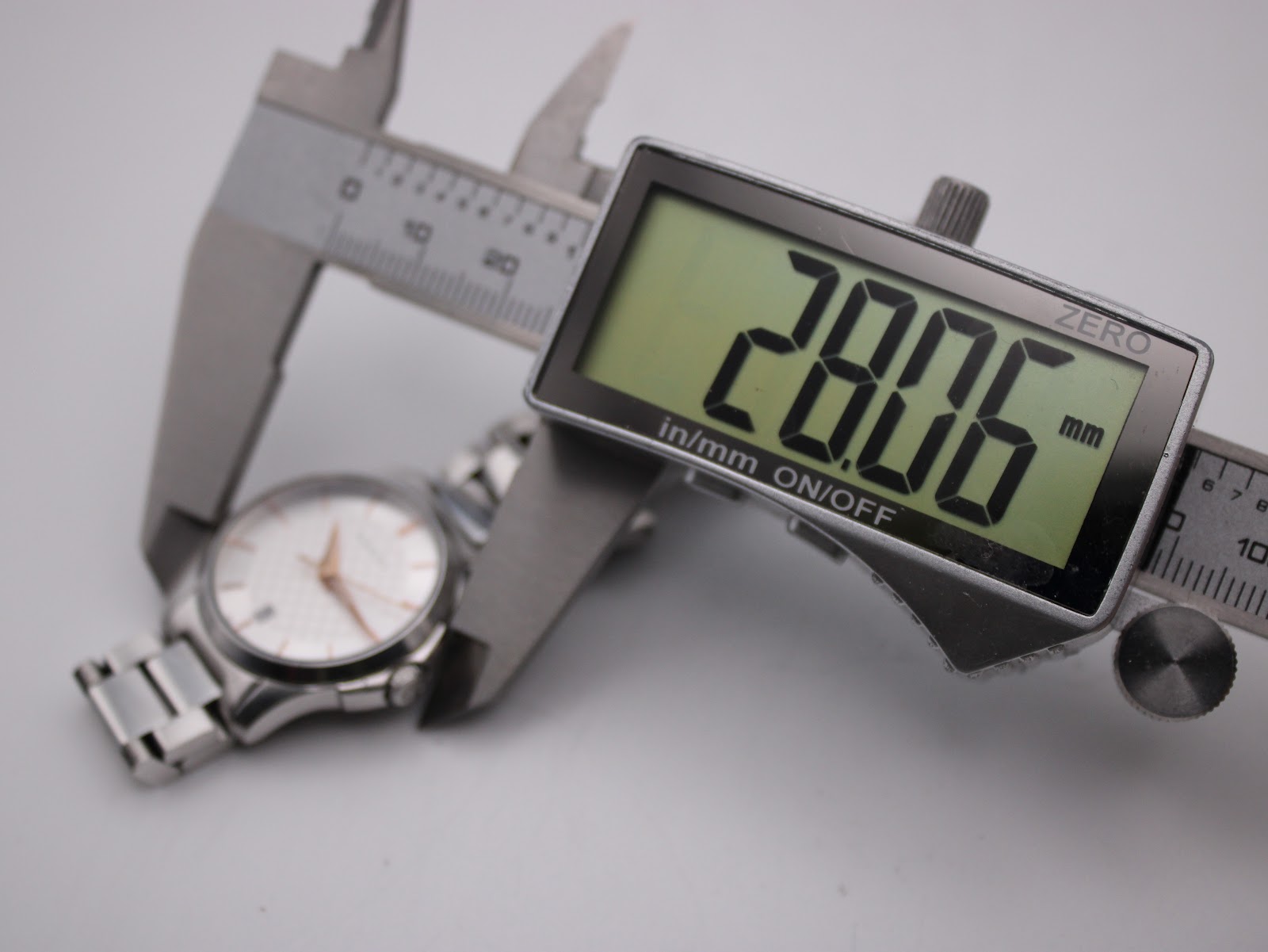 Digital caliper measuring the case diameter of the Gucci 126.5 watch, displaying a precise measurement of 28.06mm.