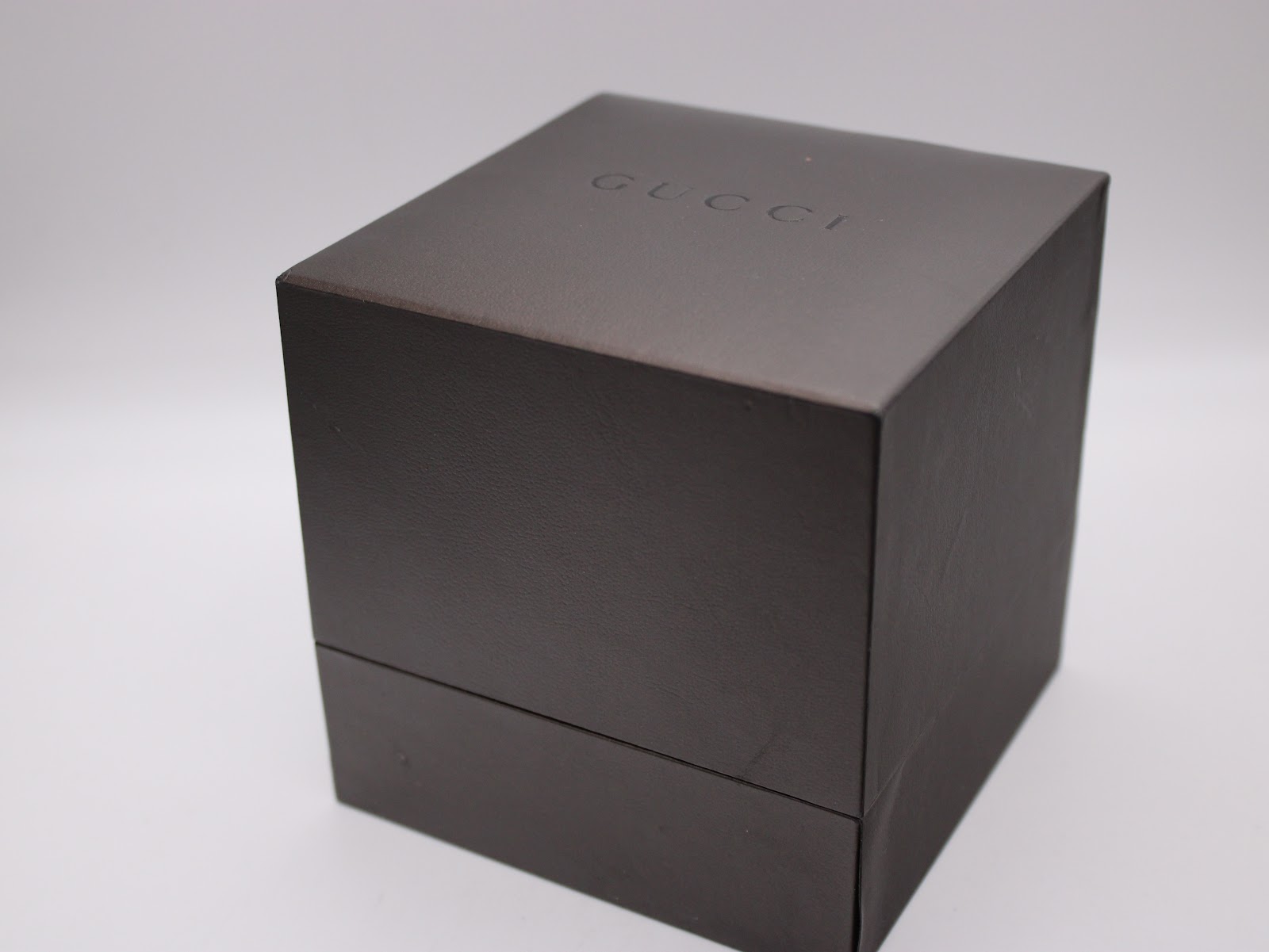 Closed original dark brown Gucci watch box with embossed logo on the lid.