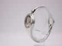 Side view of the Gucci 103 watch, showing the crown and the integrated silver bracelet, on a transparent stand.
