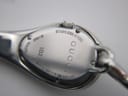 Close-up of the watch case back, showing 'GUCCI', '103', 'SWISS MADE', 'STAINLESS STEEL', 'WATER RESISTANT 3 ATM', and serial number 'c.2961'.