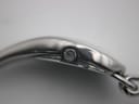 Extreme close-up of the watch crown on the side of the silver oval case.