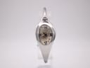 Close-up front view of the Gucci 103 watch on a clear stand, showcasing the cream floral dial and polished silver oval case.