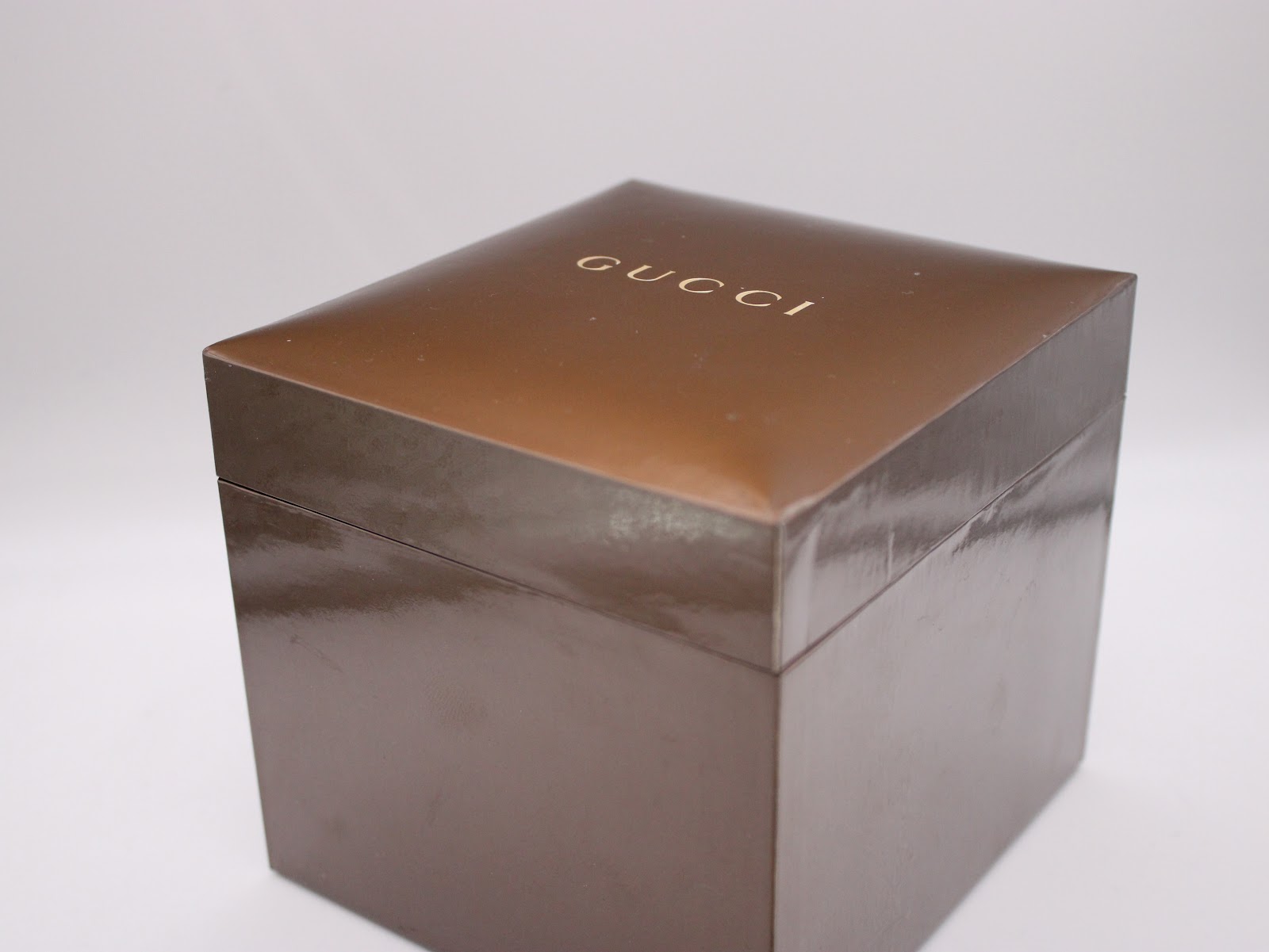 Top-down view of the closed original brown Gucci presentation box with the gold 'GUCCI' logo embossed on the lid.