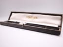 The Longines watch displayed inside its original brown presentation box with gold "LONGINES" lettering on the silk lining.