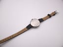 Rear view of the Longines watch on a flat surface, displaying the plain case back and the 'Genuine Leather' marking on the strap interior.