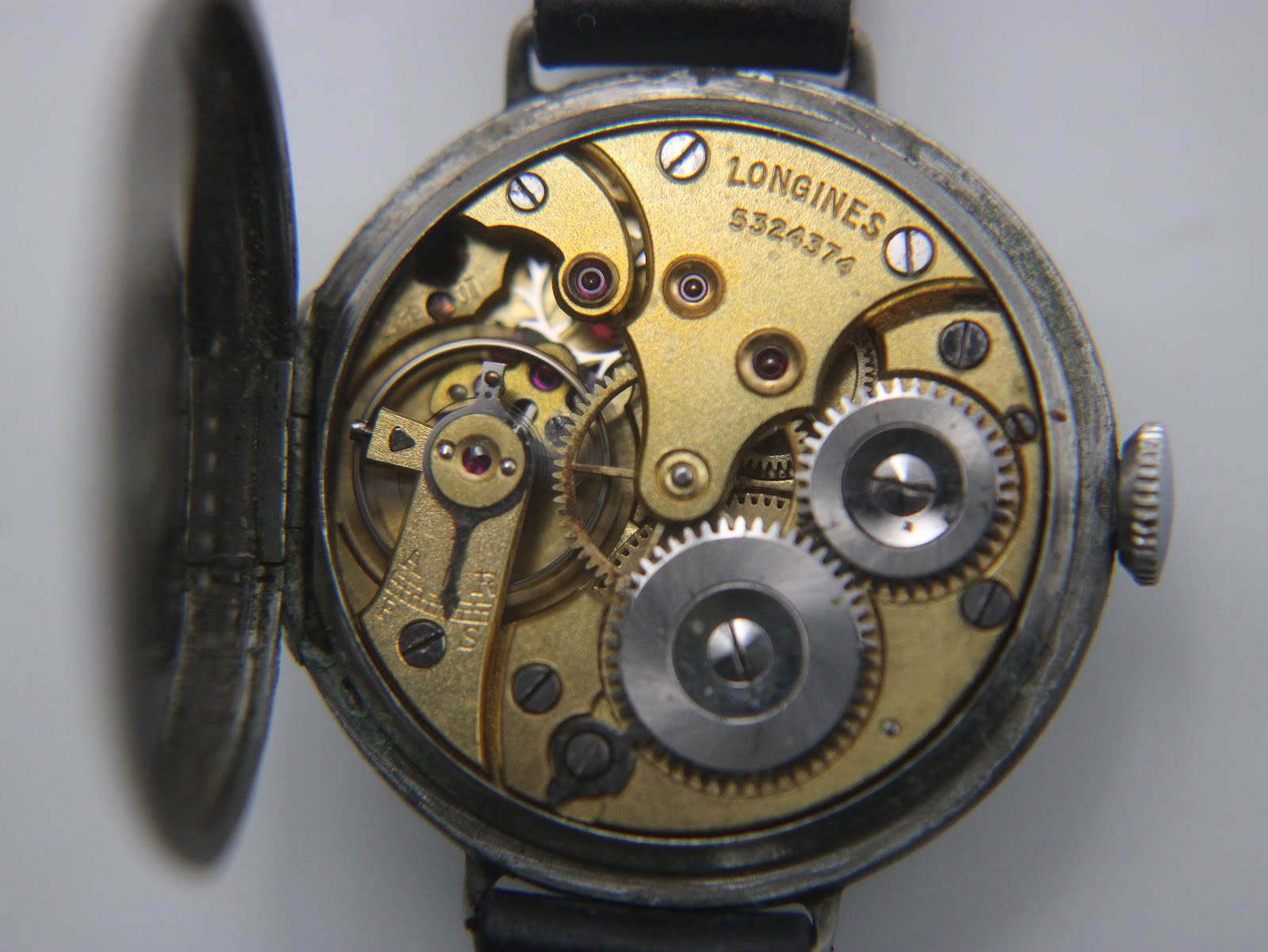 Close-up of the open hinged case back, revealing the gold-toned manual wind Longines movement with serial number 5324374.