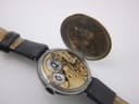 Oblique view of the Longines watch with its movement cover open, showing the intricate golden gears and balance wheel.