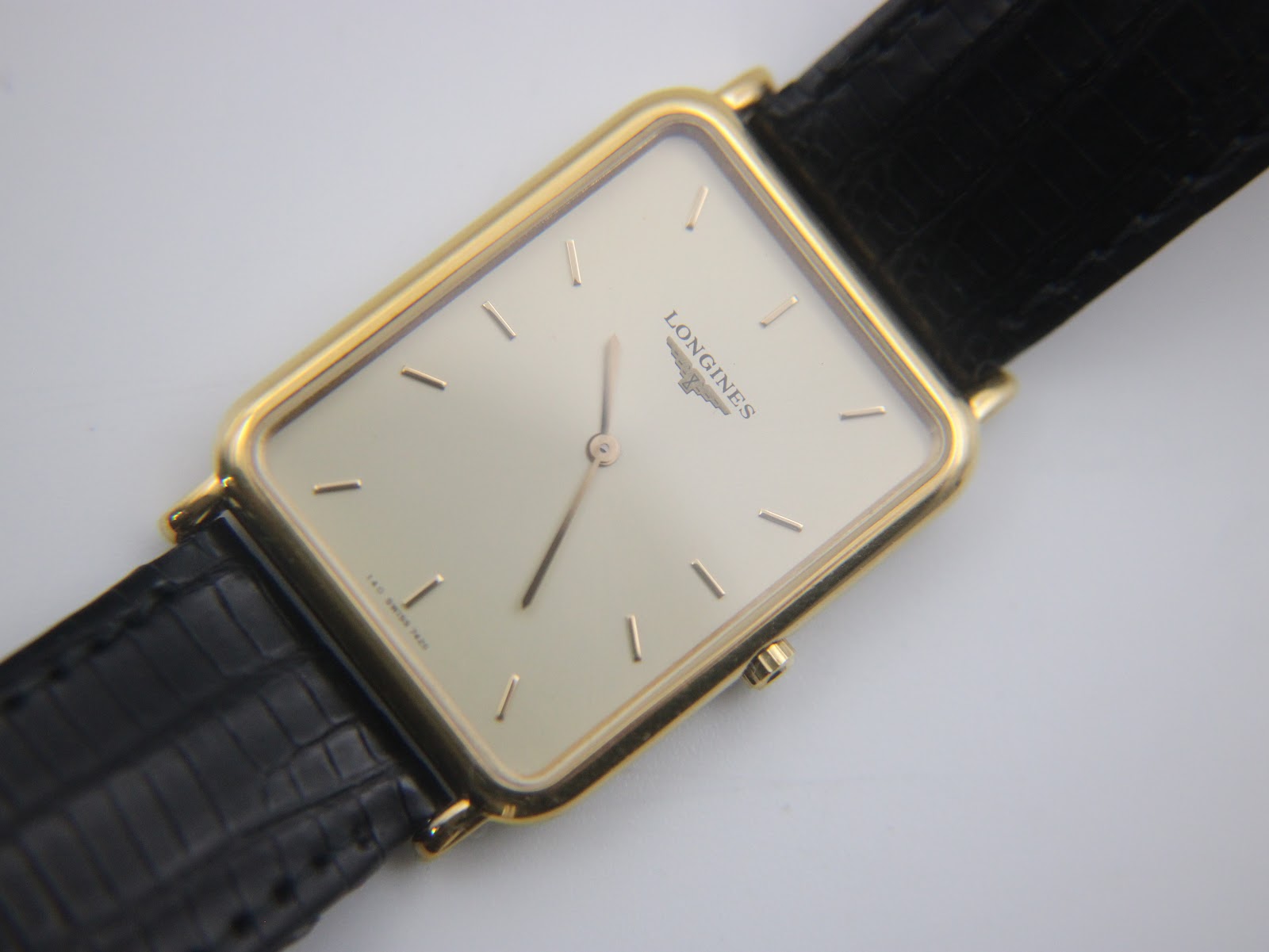 Close-up, slightly angled view of the watch dial, strap, and crown, showcasing the Longines logo and baton indices.