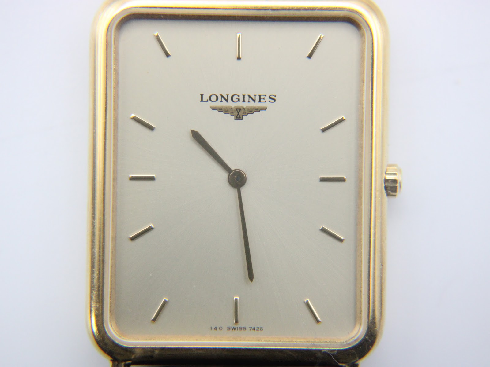Close-up, face-on view of the Longines cream dial with gold-tone baton hour markers and central hands, and the Longines logo.
