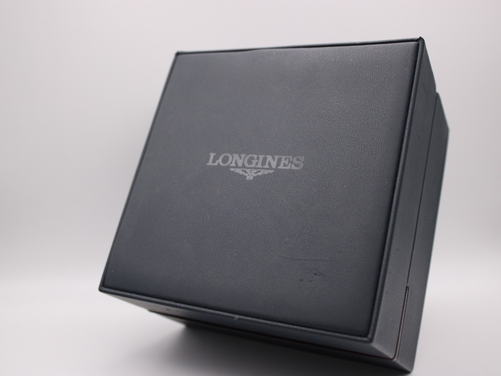 The closed original dark blue Longines watch box with the Longines logo on the lid.