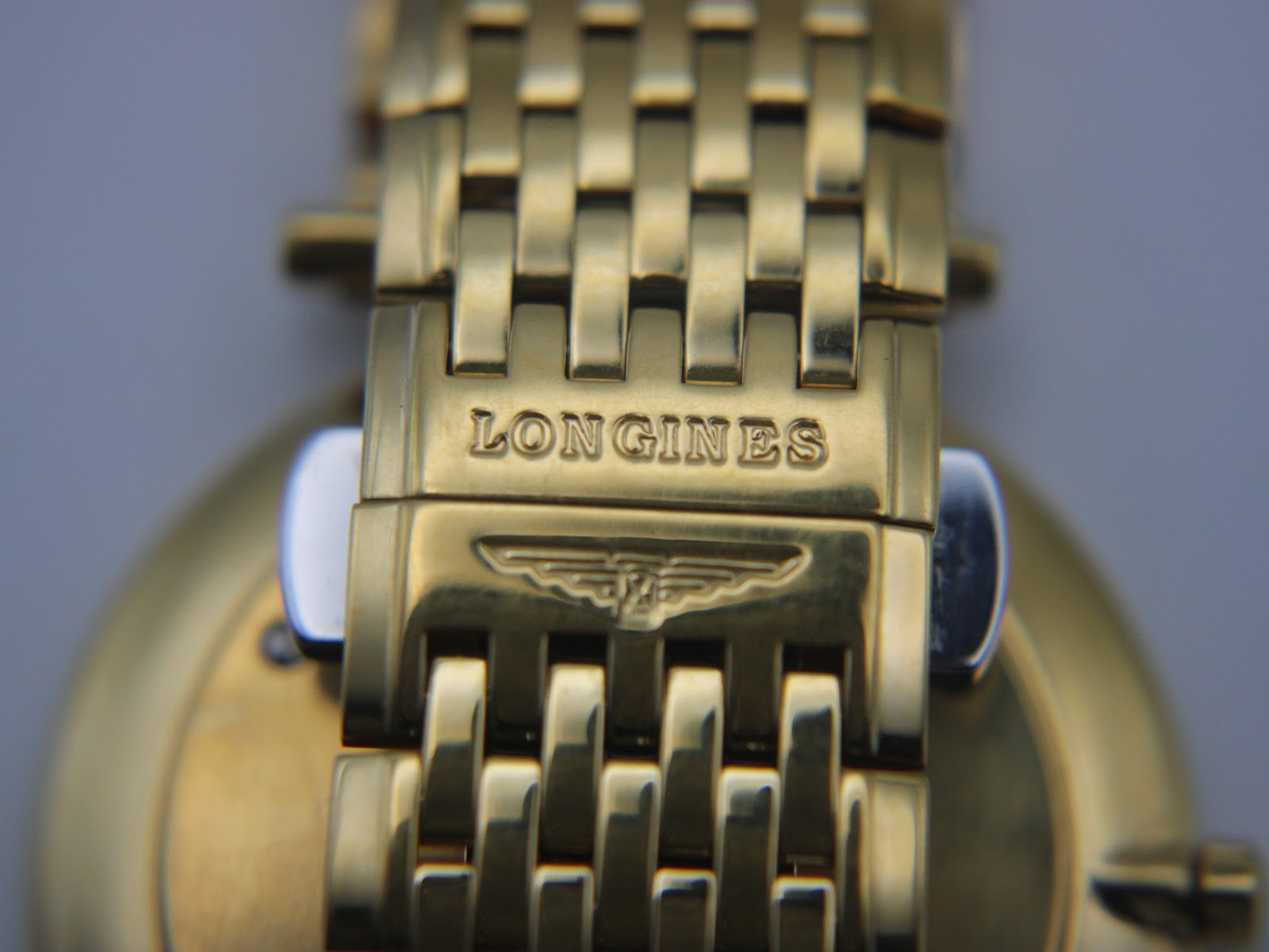 Close-up of the Longines signed deployment clasp on the gold multi-link bracelet.