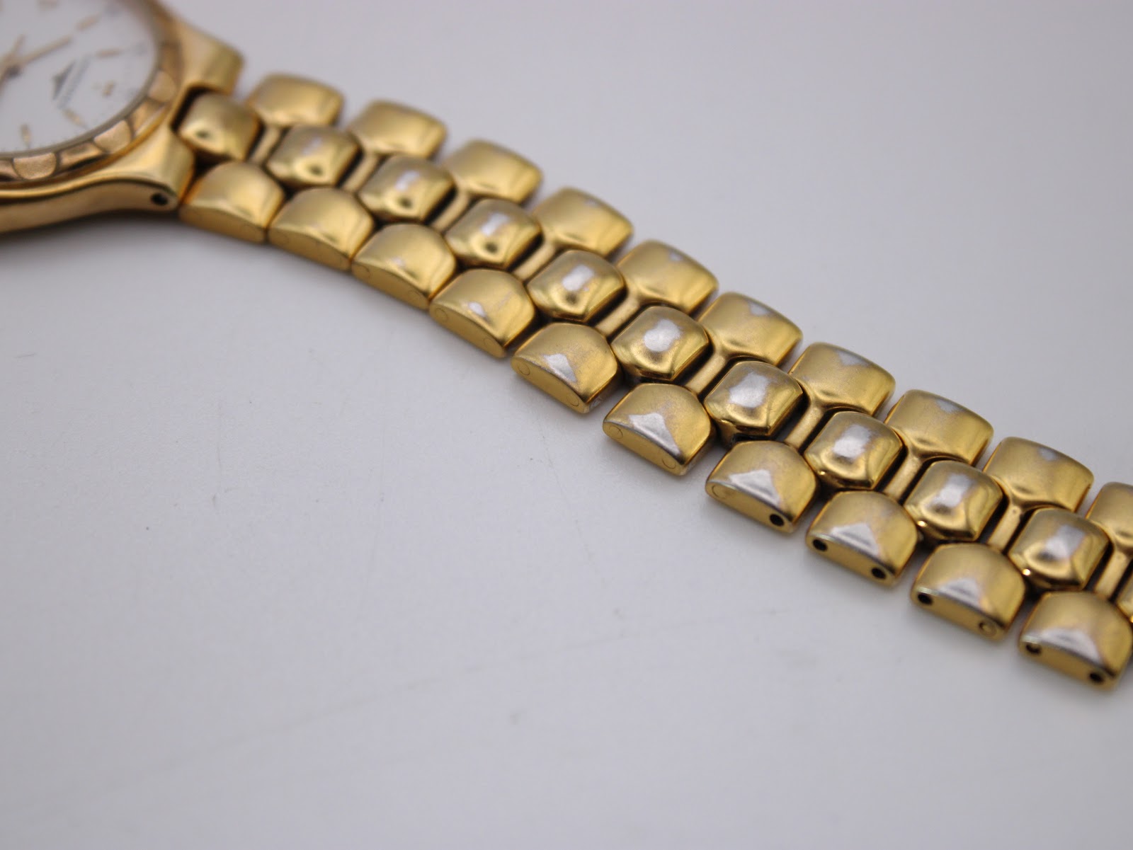 Close-up of the gold-tone integrated bracelet links, showing some wear on the underside/edges.