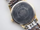Extreme close-up of a ding or chip on the gold-tone plating on the side of the watch case, near the crown.