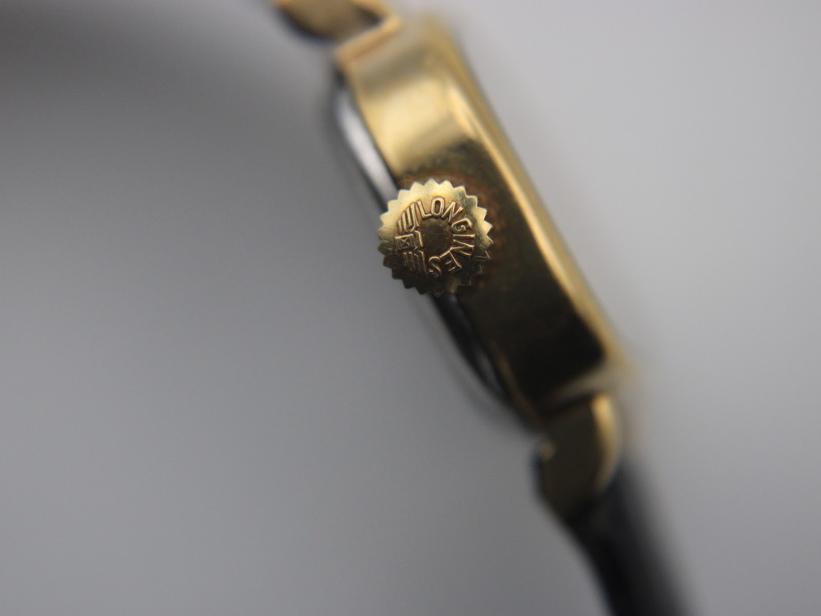 Close-up of the signed Longines crown on the side of the gold case.