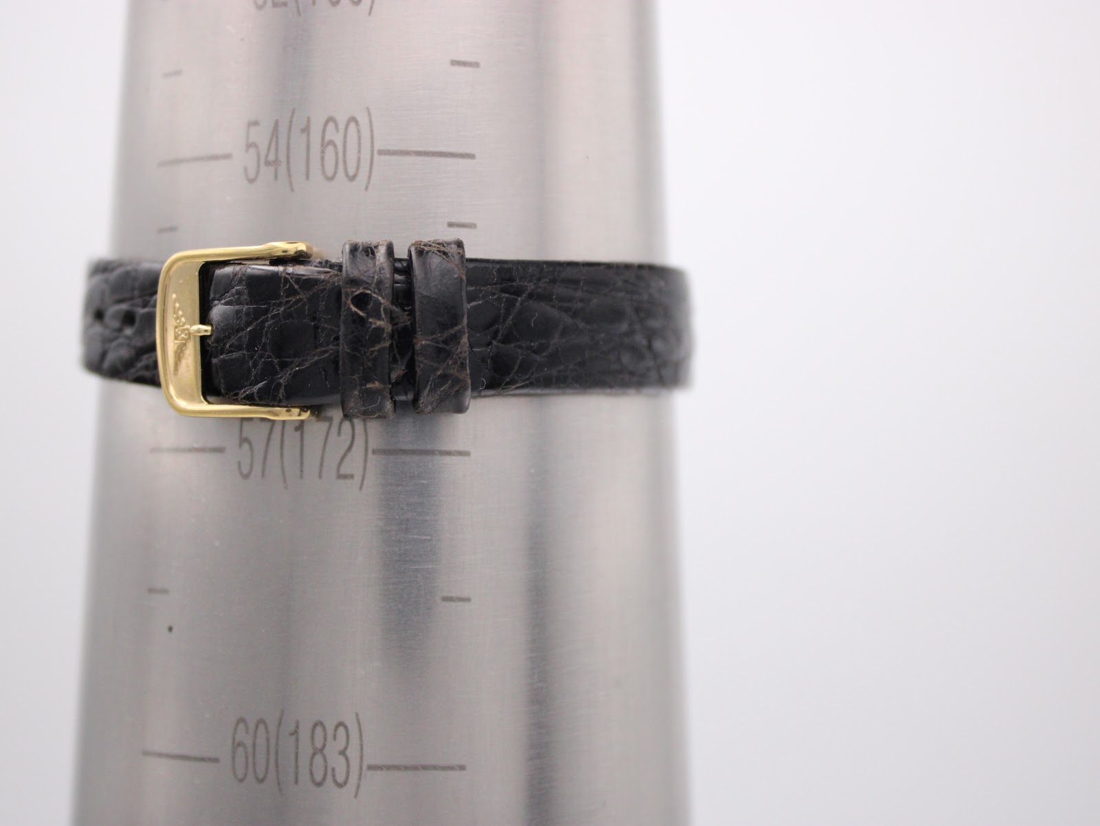 Watch strap on a wrist sizing gauge, showing a wrist circumference of approximately 16cm (6.3 inches).