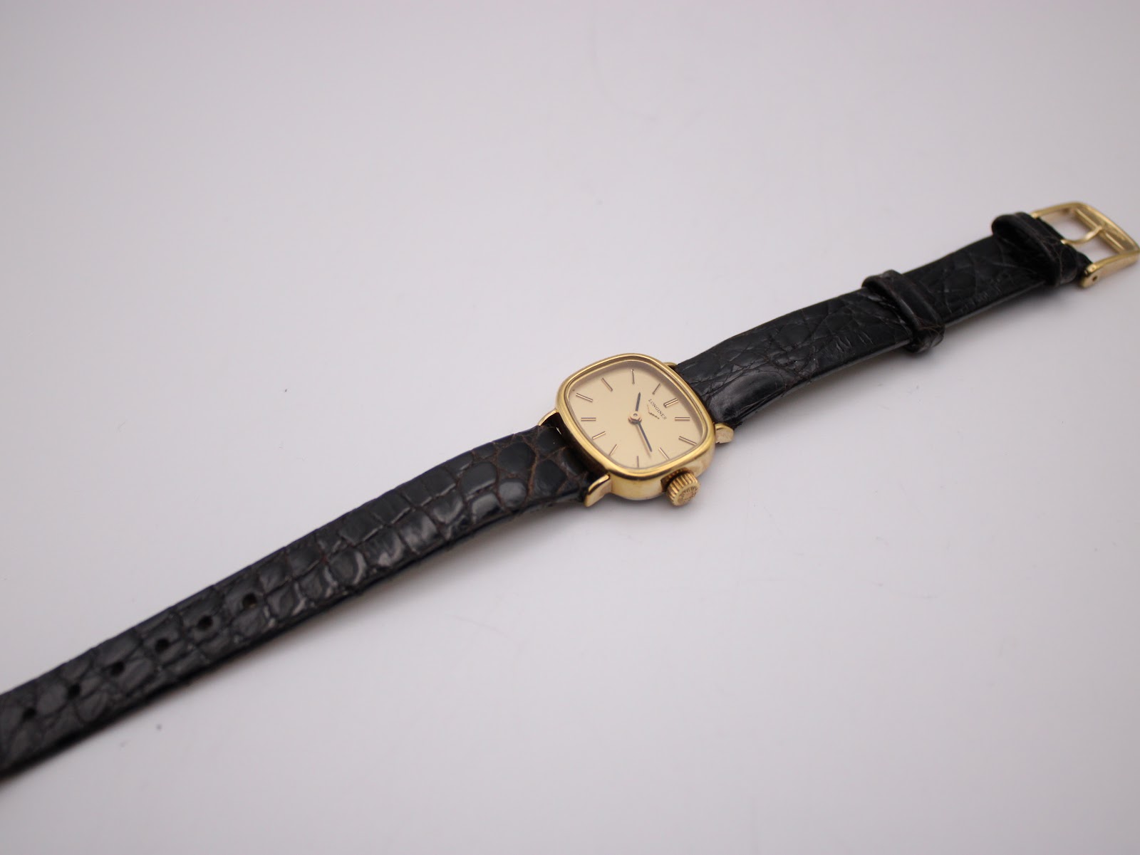 Top-down view of the Longines watch with its black leather strap laid flat.
