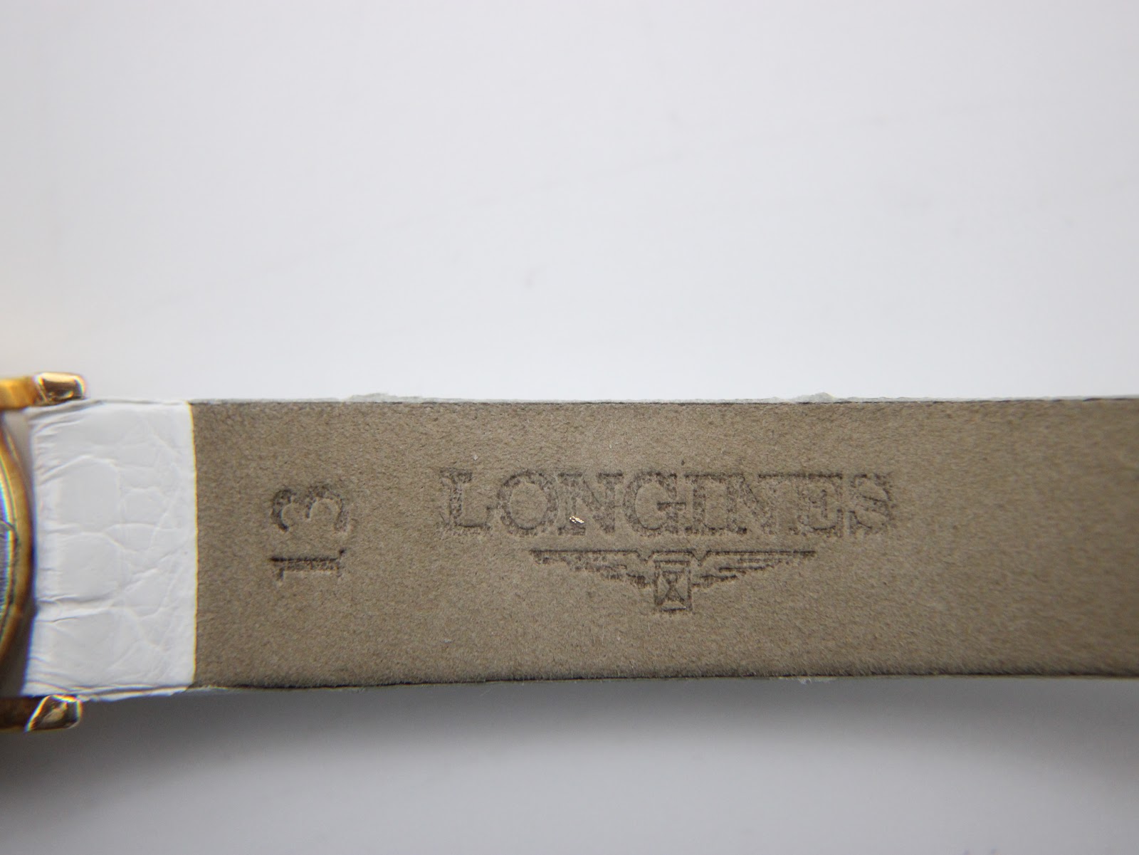 Underside of the white leather strap, clearly showing the embossed "LONGINES" logo and "13" indicating the lug width.