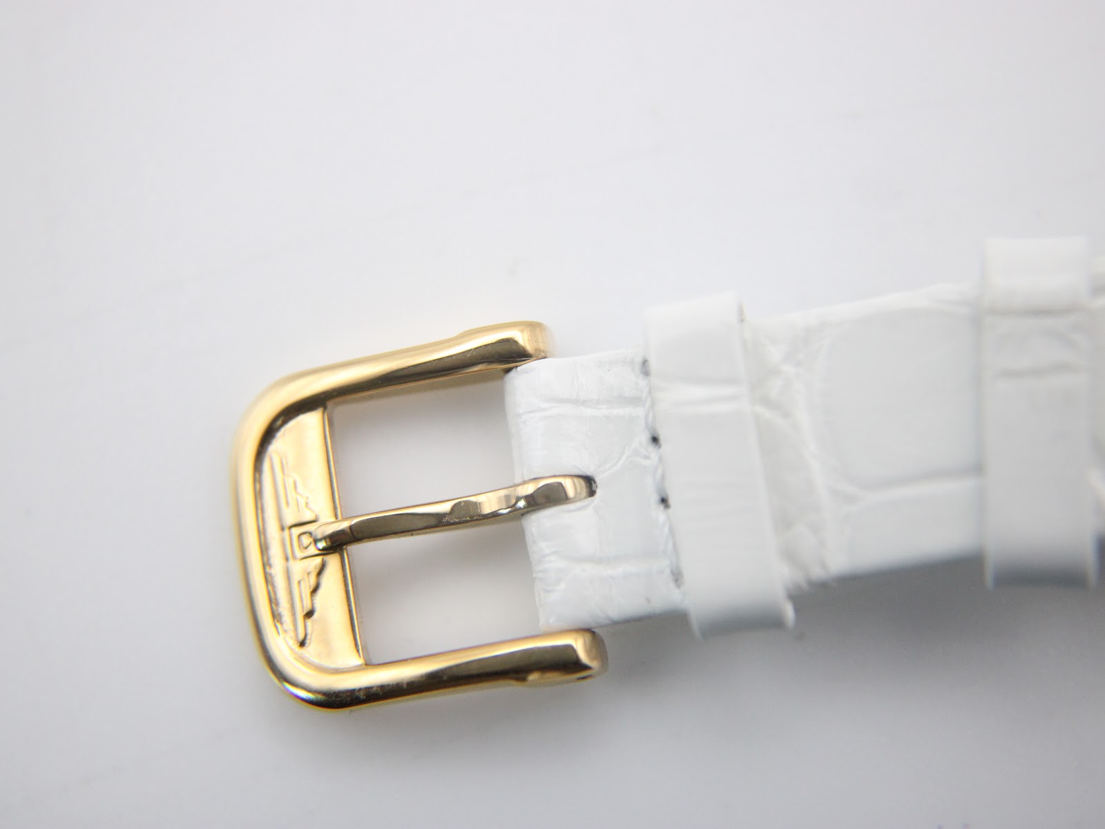 Close-up shot of the gold-tone buckle, showing its classic design.