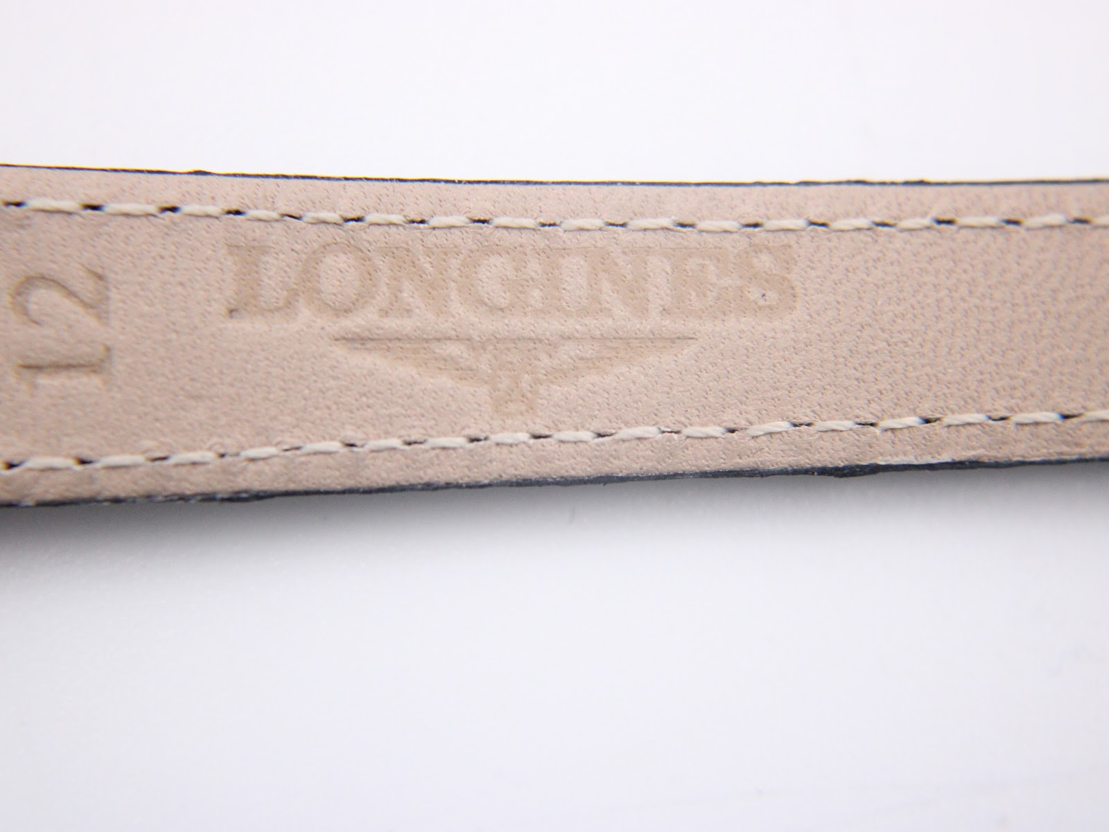 Close-up of the reverse side of the black leather strap, showing the embossed 'Longines' logo and '12' (indicating lug width).