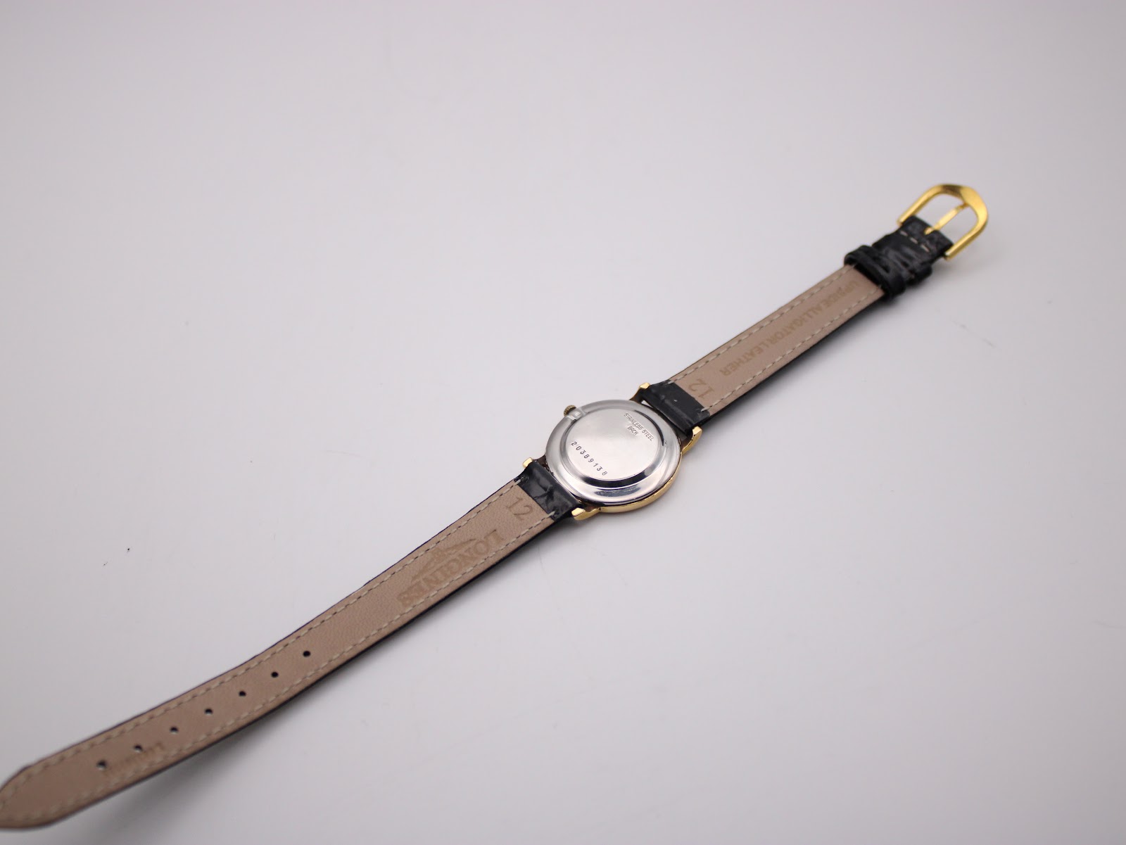Rear view of the Longines watch, displaying the polished stainless steel case back and the full length of the black leather strap with its gold-tone buckle.