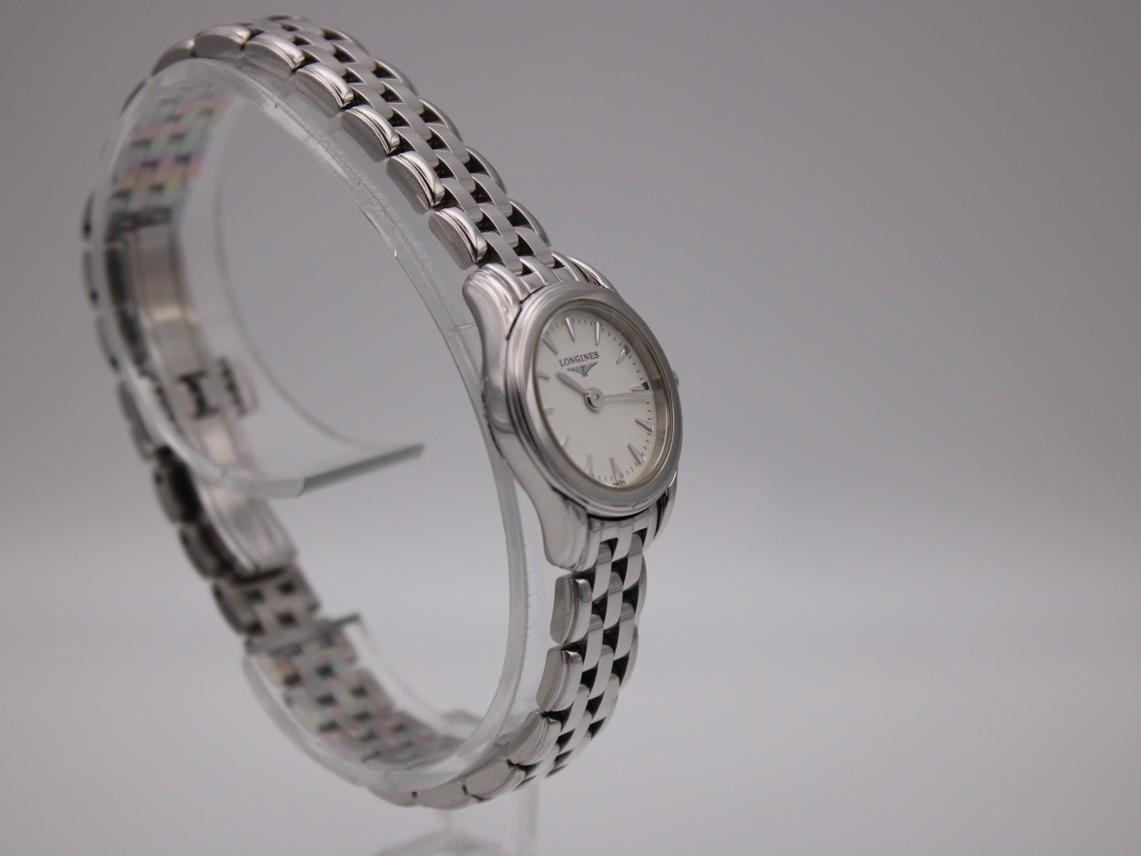 Oblique front view of the Longines L4.215.4 watch on a clear stand, showcasing the dial and polished finish.