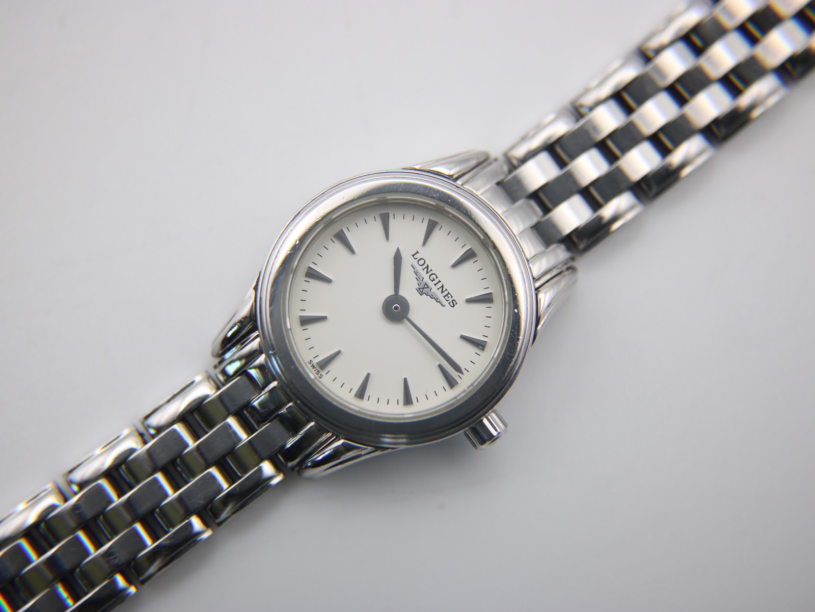 Detailed close-up of the white dial with Longines logo, baton hour markers, and black hands.