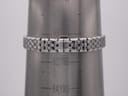 Close-up of the stainless steel bracelet and signed clasp on a wrist sizing cone, showing a wrist circumference of approximately 18.3cm.