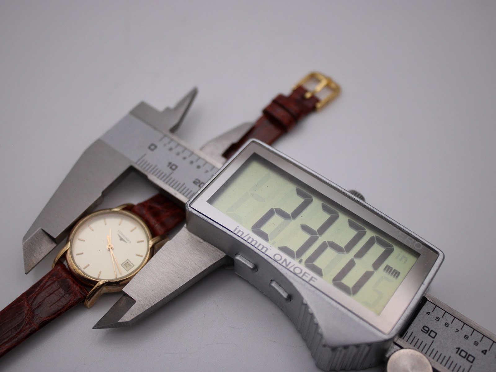 Watch case being measured by a digital caliper, displaying a precise diameter of 22.20mm.