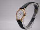 Angled right-side view of the Longines Presence watch showing the gold case, crown, and green leather strap.