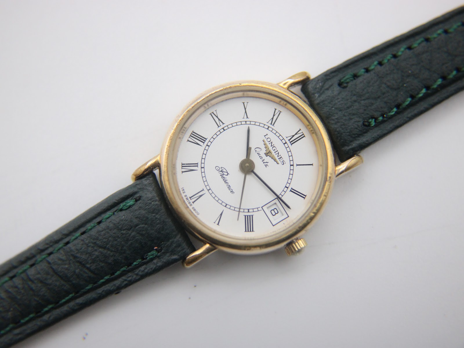 Overhead flat lay view of the Longines Presence watch with its white dial and green leather strap.