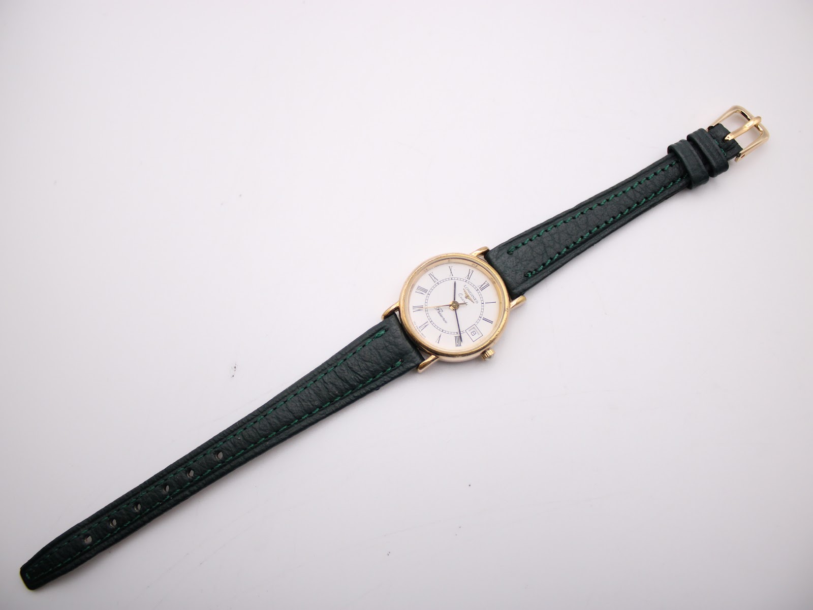 Full length view of the Longines Presence watch and green leather strap laid flat.